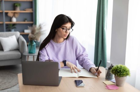 woman-sitting-at-desk-using-computer-and-writing-2022-12-16-07-41-55-utc (1)